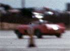Blurred photo: unidentified, finned, red car