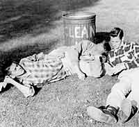 Thumbnail: Ronnie Busch, Charlie Babbitt, Richard Gatley lying next to a "Clean Up" trash can