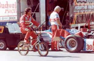 Thumbnail: Mario Andretti biking in the garage area, just prior to signing my t-shirt  CLICK to see a larger version